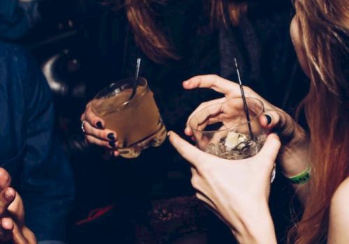People are enjoying drinks and sharing a laugh in a lively social setting, captured in a candid moment.