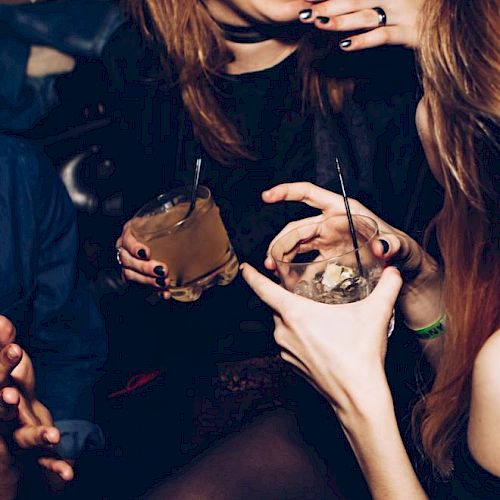 People are enjoying drinks and sharing a laugh in a lively social setting, captured in a candid moment.