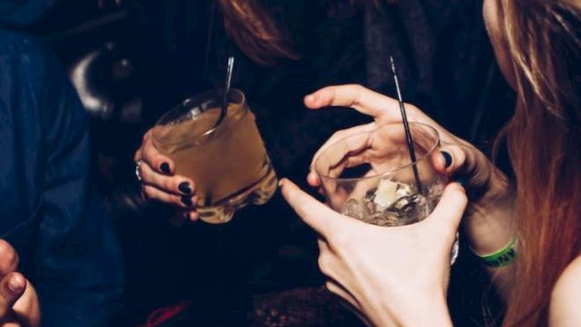 People are enjoying drinks and sharing a laugh in a lively social setting, captured in a candid moment.