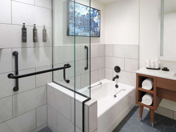 A modern bathroom with a glass-enclosed shower, a tub, a sink with a wooden cabinet, and a hexagonal tile floor.