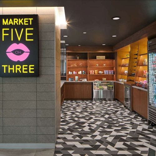 The image shows a modern convenience market with a neon "Market Five OH Three" sign and shelves stocked with snacks and drinks.