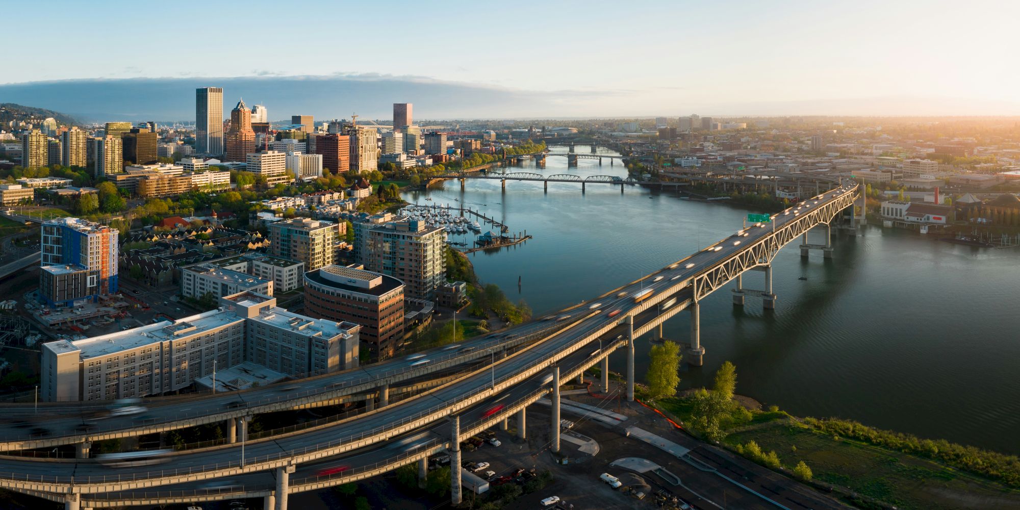 Aerial view of a cityscape with bridges, buildings, and a river under a clear sky, showcasing urban architecture and waterways.