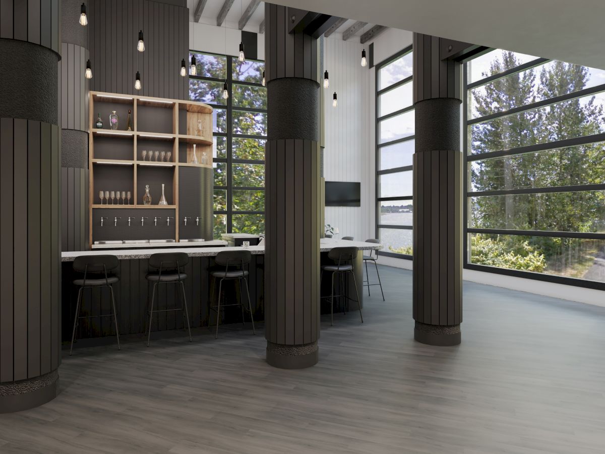 A modern interior with tall windows, a bar area with stools, columns, and hanging lights, offering a view of trees outside the large windows.