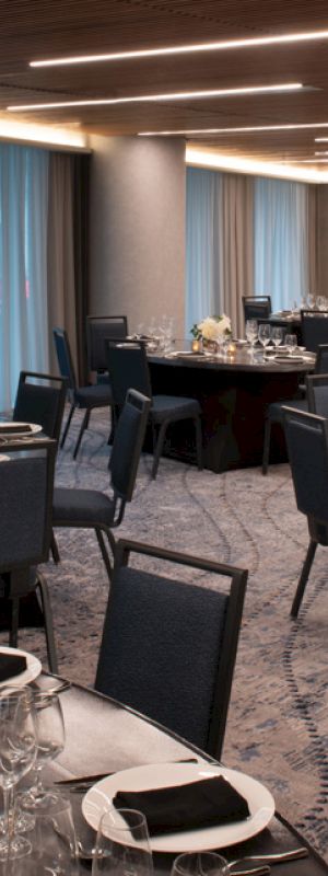 The image shows an elegantly set banquet hall with round tables, chairs, and decorative table settings, ready for an event.